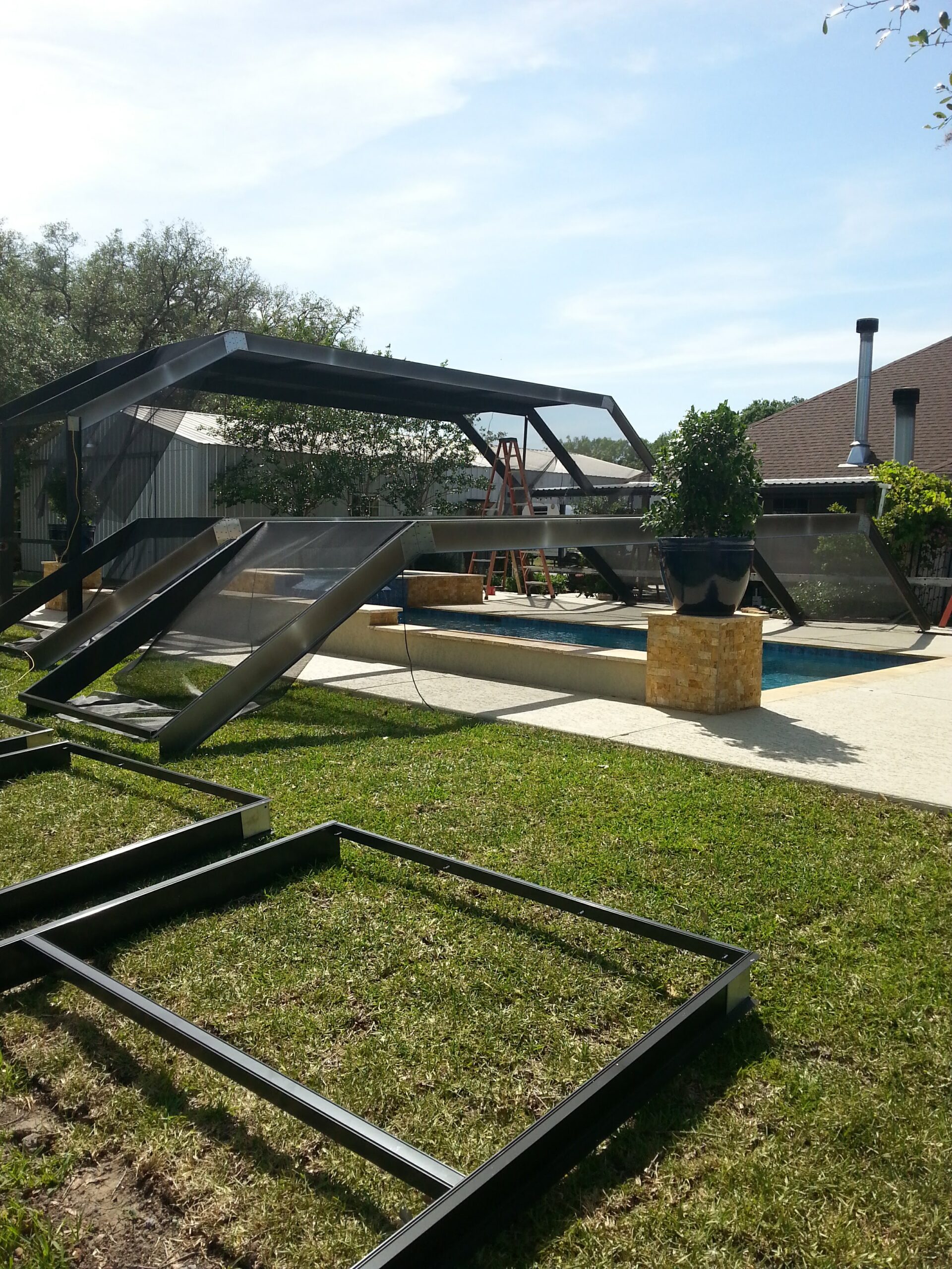 Bronze aluminum pool cage frame being assembled in a Webster, TX backyard