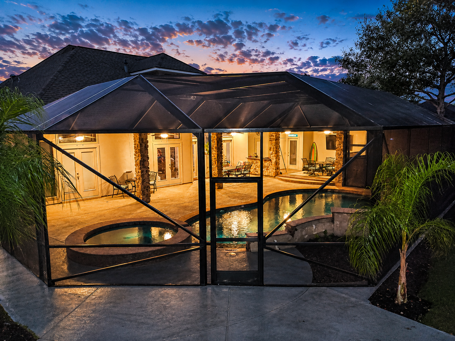 Pool enclosure lit up at night by Simmons Home Design